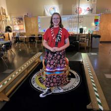 Indigenous Student standing, wearing a Ribbon Skirt. Wearing ribbon skirt symbolizes indigenous pride and serves as a powerful connection to identity, resilience and survival. 